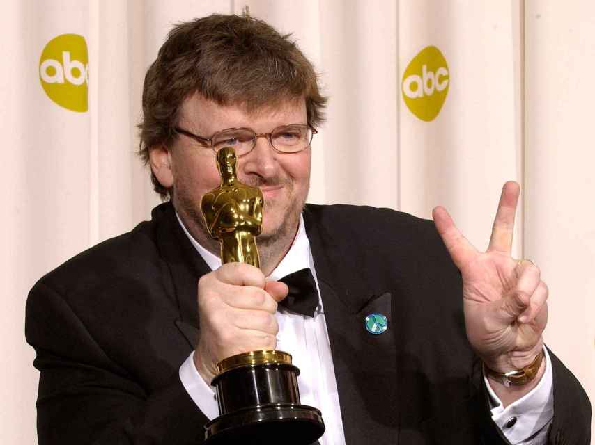 Michael Moore posa y hace el gesto de la paz con su Oscar al Mejor documental.