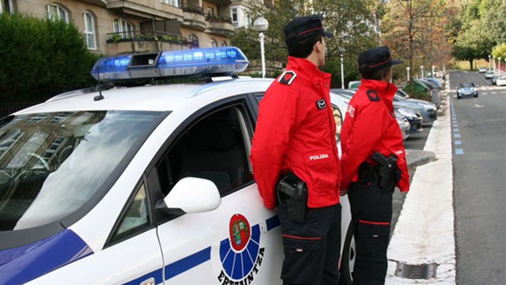 Dos agentes de la Ertzainza, la policía autonómica vasca, junto a su vehículo.