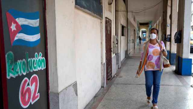 Una mujer camina hoy junto a un dibujo en apoyo a la Revolución Cubana, en La Habana.