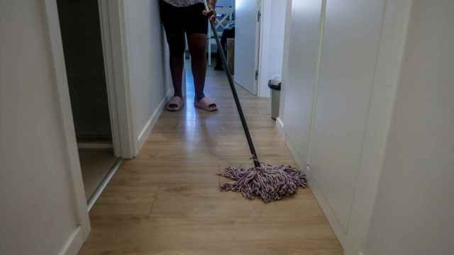 Una empleada de hogar limpia con una fregona.